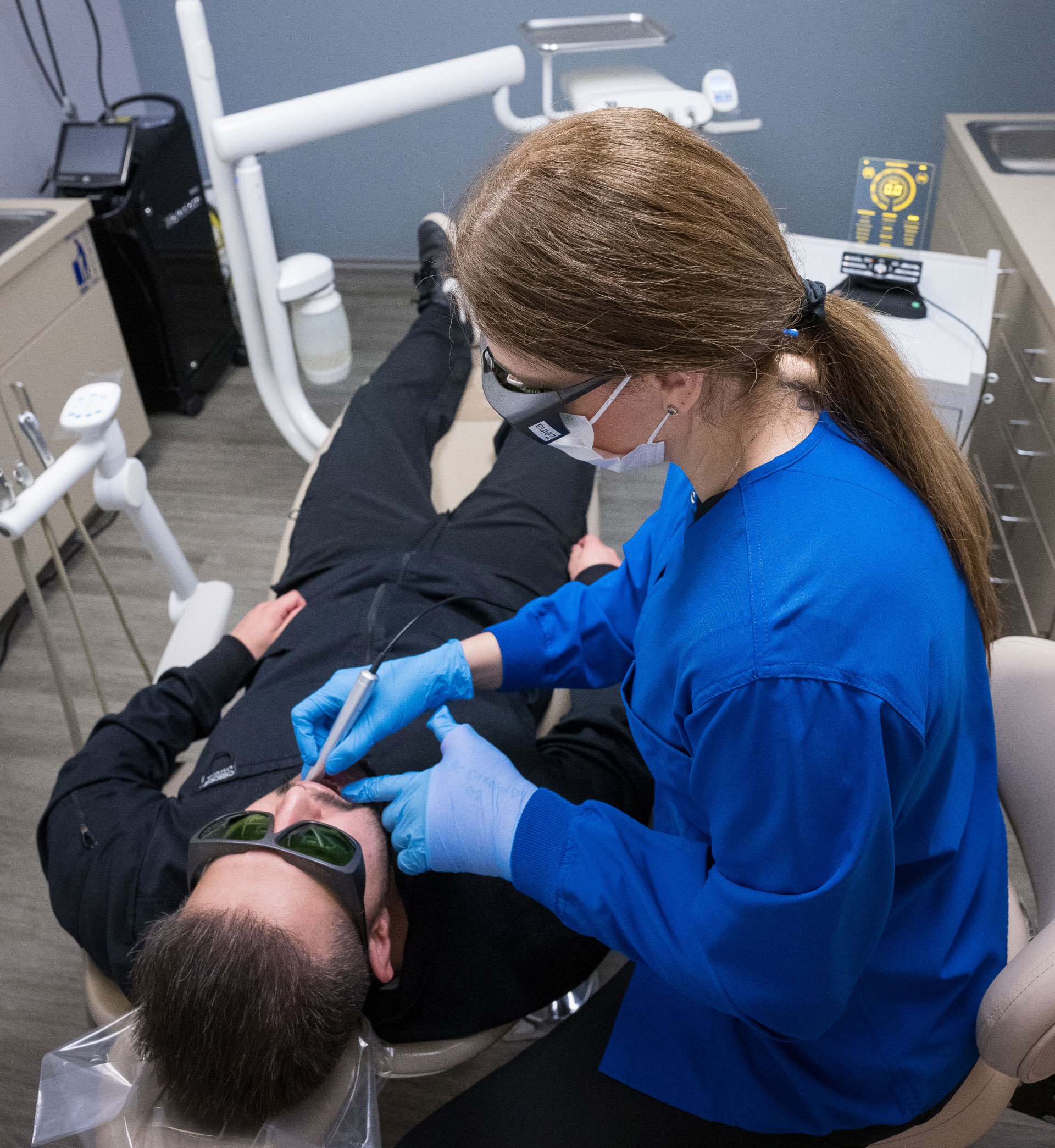 assistant using laser on patient during dental exam